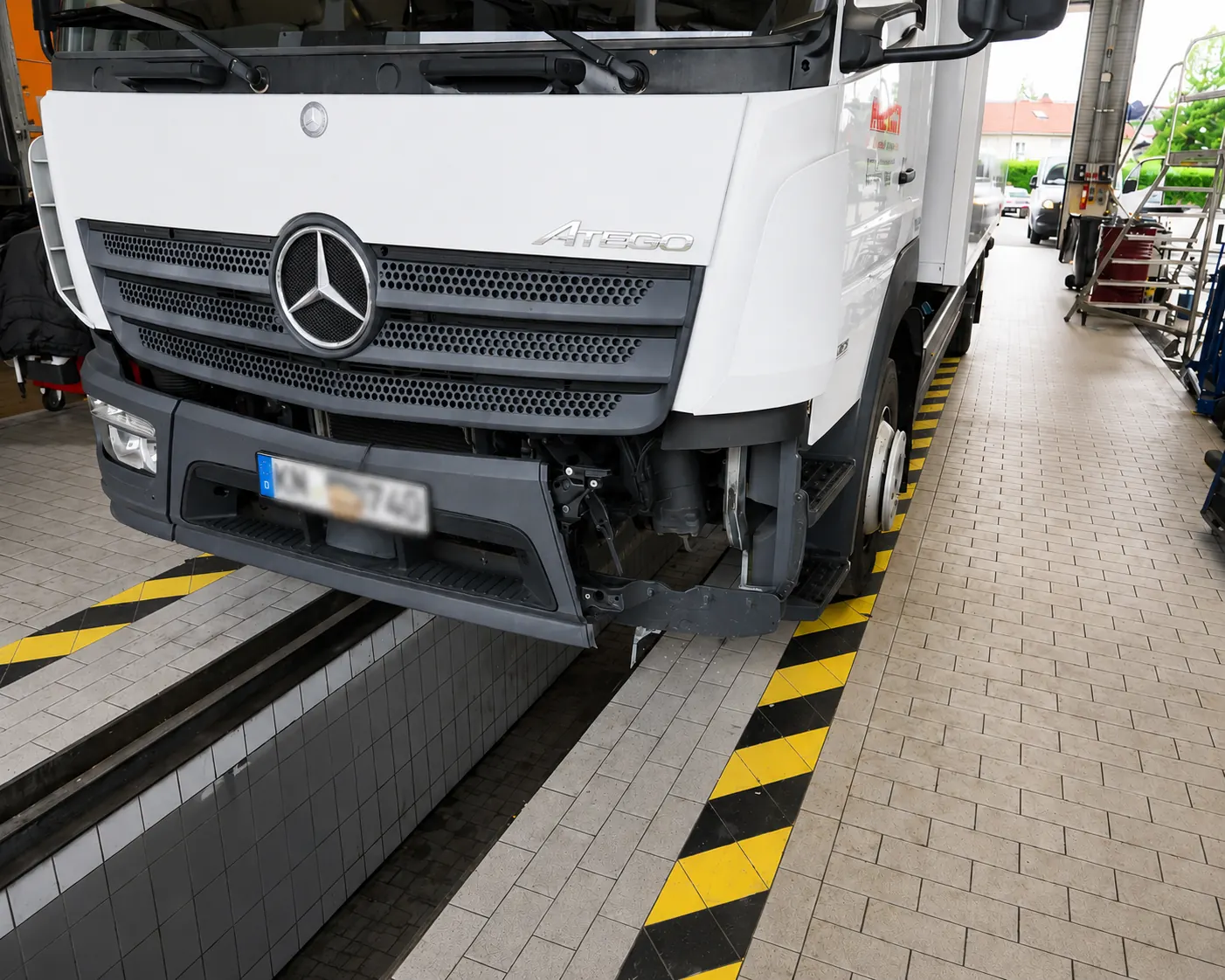 Mercedes-Lkw Atego mit beschädigter Front über einer Werkstattgrube