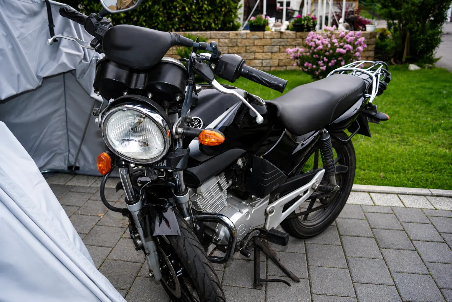 Schwarzes Motorrad mit rundem Scheinwerfer und Gepäckträger vor einem Motorrad-Garagenzelt