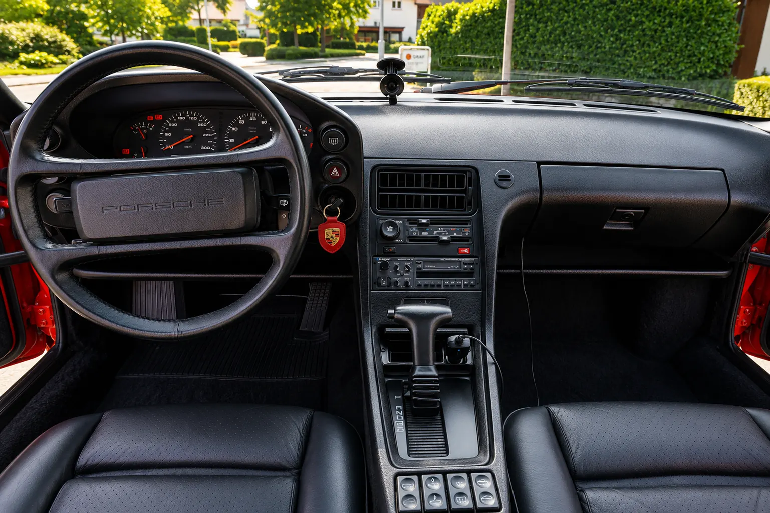 Cockpit eines klassischen Porsche mit Porsche-Lenkrad, Rundinstrumenten und schwarzen Ledersitzen